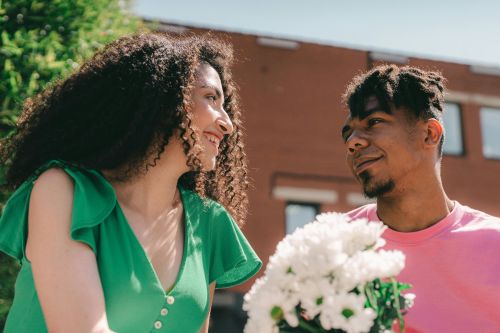 Happy couple in love sharing a tender moment with a bouquet of flowers outdoors.