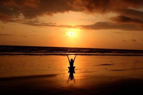 Peaceful meditation silhouette at sunset on a serene beach.