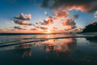 A beautiful sunrise over Kailua Beach with vibrant clouds reflected in the calm ocean water.