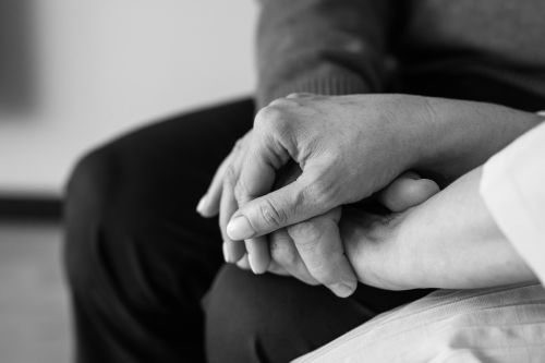 Black and white image of two hands holding, conveying comfort and support, close-up view.