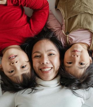 Joyous mother with her children lying on bed, capturing a happy moment of togetherness.