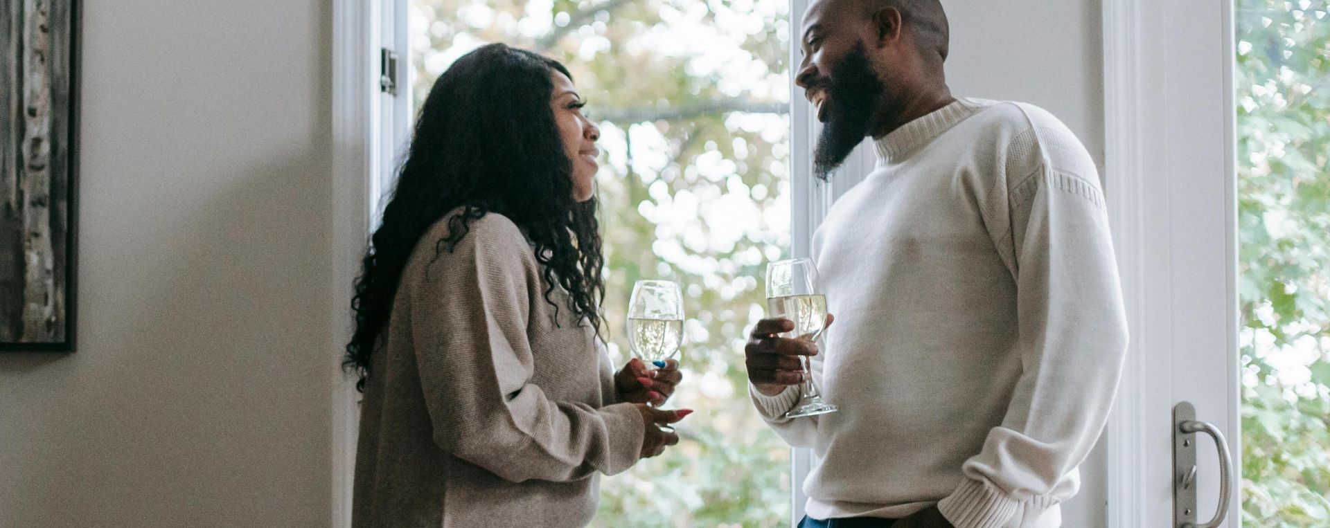 African American couple enjoying Christmas with wine and festive decor at home.