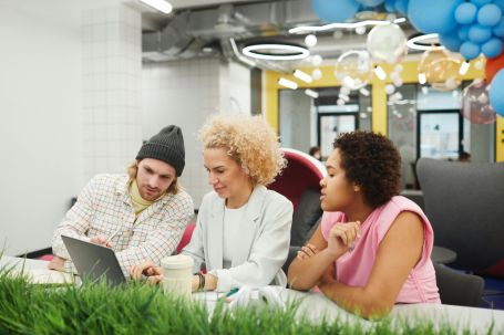 Diverse group of young professionals collaborating on a project in a vibrant office space.