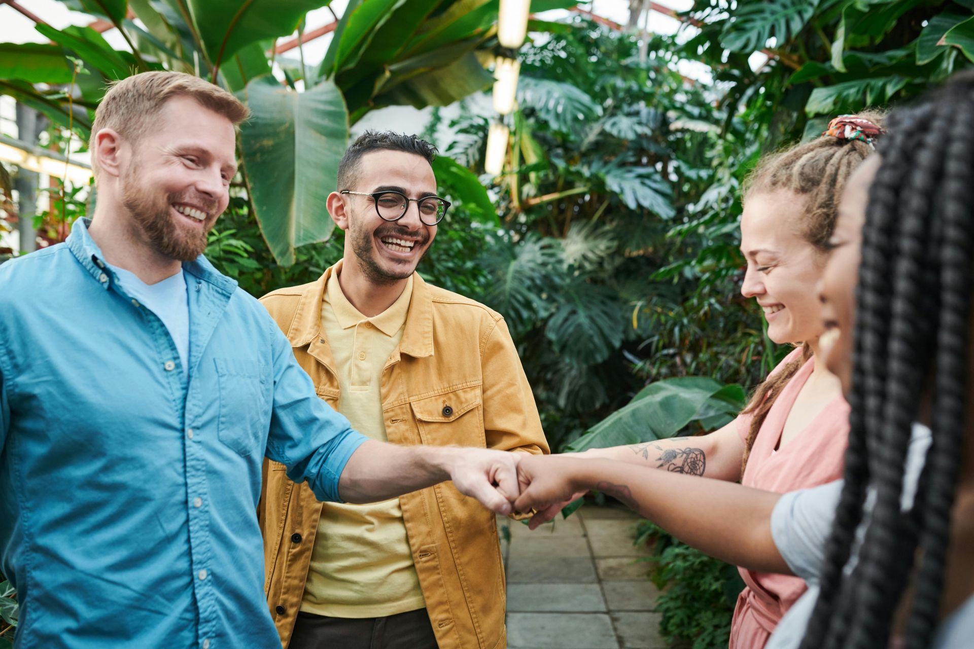 Diverse colleagues share a joyful high five, showcasing teamwork and unity in the office.